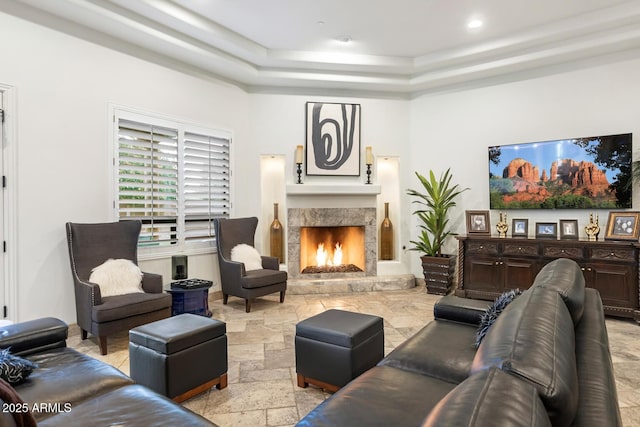 living room with a premium fireplace and a raised ceiling