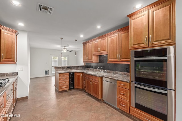 kitchen featuring appliances with stainless steel finishes, tasteful backsplash, sink, ceiling fan, and kitchen peninsula