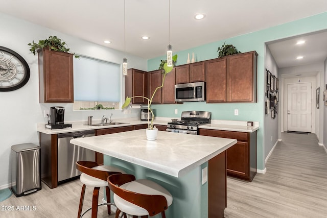 3415 S 75th Dr, Phoenix, AZ 85043 - kitchen featuring stainless steel appliances, a sink, light wood finished floors, light countertops, and a kitchen island