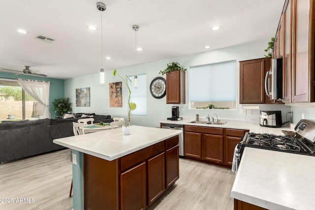 3415 S 75th Dr, Phoenix, AZ 85043 - kitchen featuring appliances with stainless steel finishes, a sink, open floor plan, light wood finished floors, and light countertops