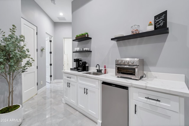 kitchen with white cabinets, light stone counters, sink, and fridge