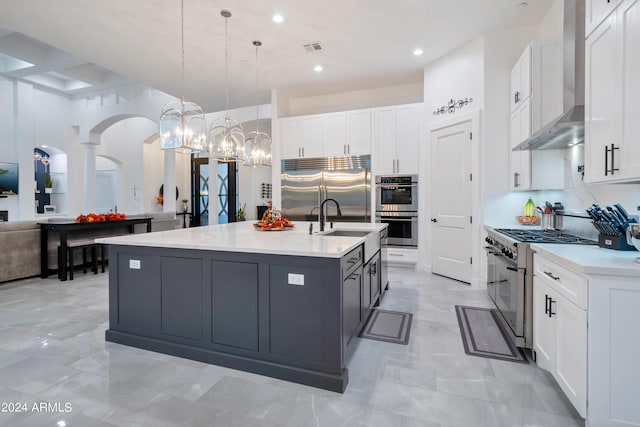 kitchen featuring white cabinets, pendant lighting, high quality appliances, and wall chimney range hood