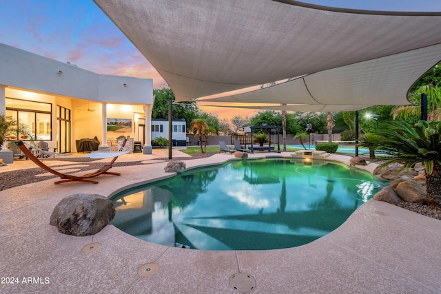 pool at dusk with a patio area