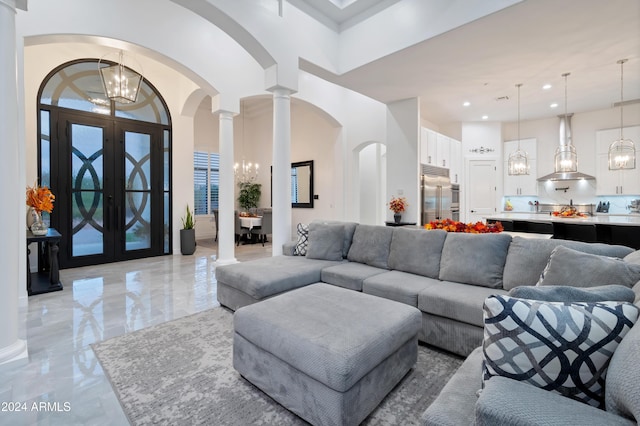 living room with a chandelier, french doors, ornate columns, and a high ceiling