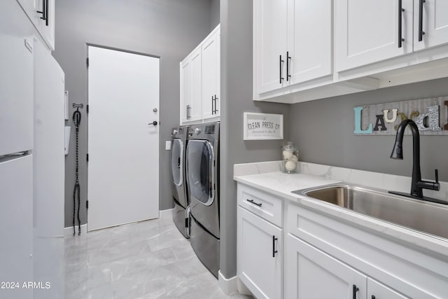 laundry room with cabinets, washing machine and dryer, and sink