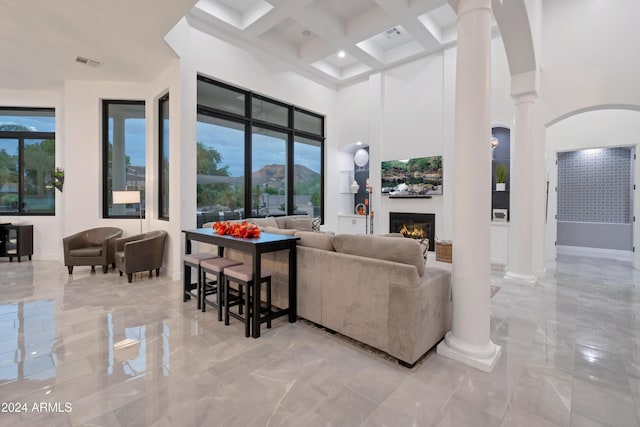 living room with beamed ceiling, ornate columns, a towering ceiling, and coffered ceiling