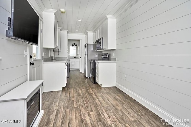 kitchen featuring white cabinetry, stainless steel appliances, dark hardwood / wood-style floors, wood walls, and ornamental molding