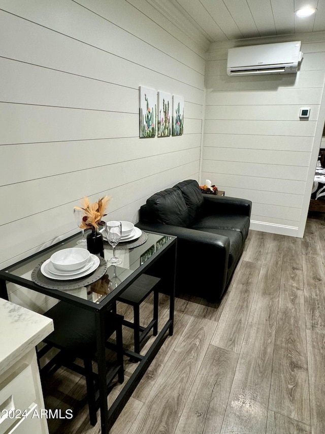 dining area with wood walls, light hardwood / wood-style flooring, and a wall mounted AC