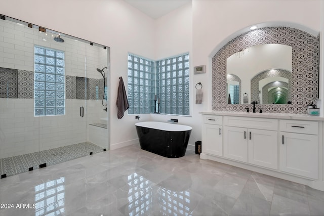 bathroom featuring plus walk in shower, vanity, and tasteful backsplash