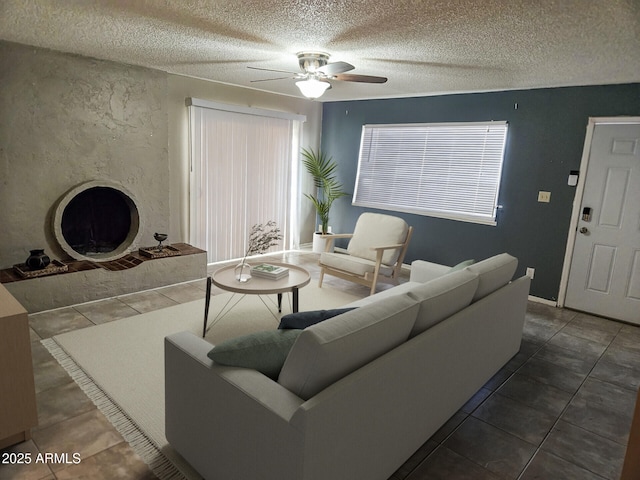 tiled living room featuring a premium fireplace, ceiling fan, and a textured ceiling