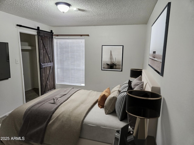 bedroom with a barn door and a textured ceiling