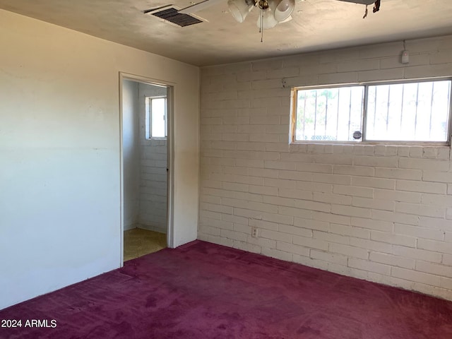 unfurnished bedroom with carpet, multiple windows, and brick wall