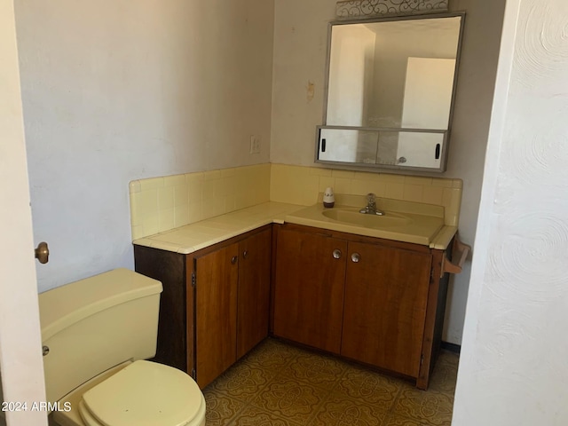 bathroom with vanity, toilet, and decorative backsplash