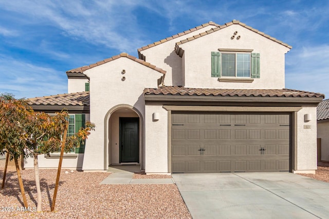 mediterranean / spanish-style house featuring concrete driveway, a tiled roof, an attached garage, and stucco siding