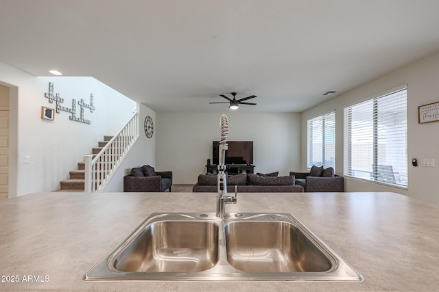 kitchen with ceiling fan, visible vents, open floor plan, and a sink