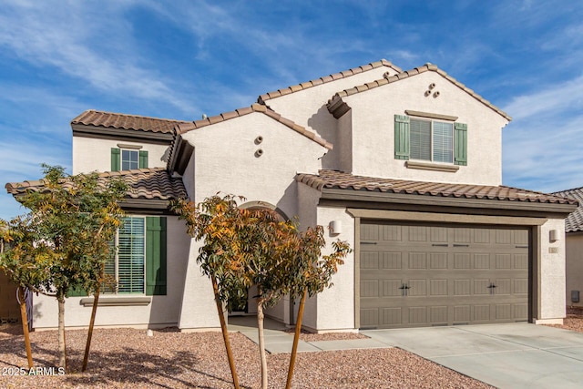 mediterranean / spanish house with an attached garage, a tiled roof, concrete driveway, and stucco siding