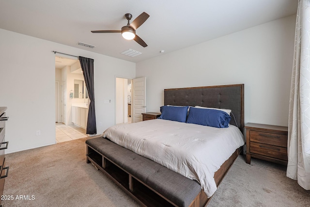 bedroom with ensuite bath, visible vents, a ceiling fan, and light colored carpet