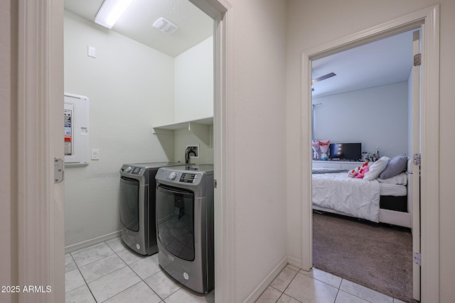 washroom with light tile patterned floors, laundry area, washing machine and dryer, and baseboards