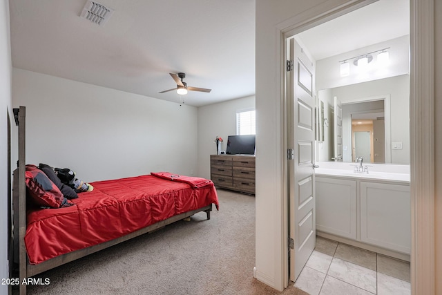 bedroom featuring light tile patterned floors, ceiling fan, light colored carpet, a sink, and visible vents