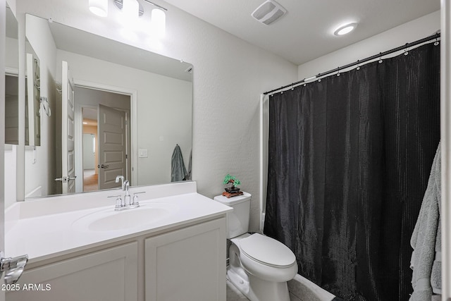 bathroom featuring visible vents, a textured wall, vanity, and toilet