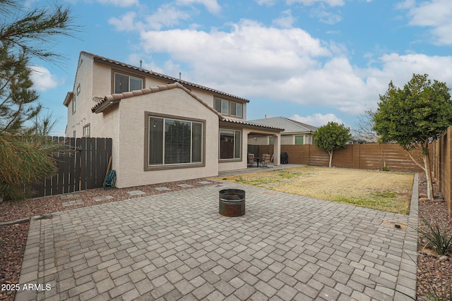 back of house featuring an outdoor fire pit, a fenced backyard, a tile roof, stucco siding, and a patio area