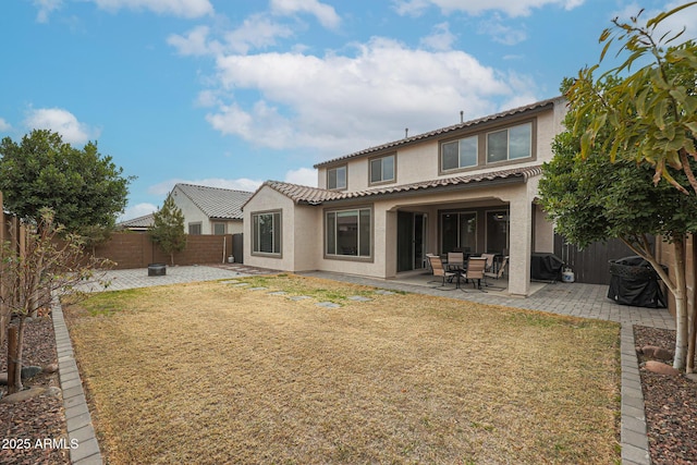 rear view of property with stucco siding, a fenced backyard, a lawn, and a patio