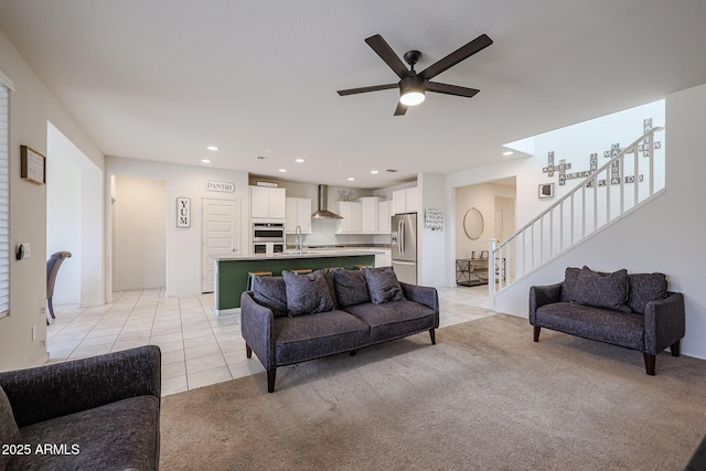 living area featuring ceiling fan, light tile patterned flooring, recessed lighting, light carpet, and stairs