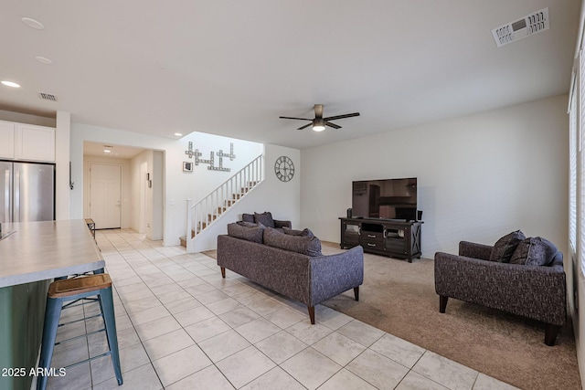 living area featuring light tile patterned floors, visible vents, light carpet, and stairs