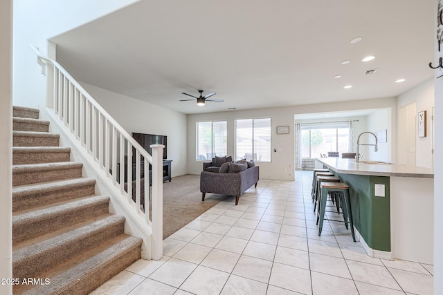 living area featuring light tile patterned floors, ceiling fan, recessed lighting, visible vents, and stairway