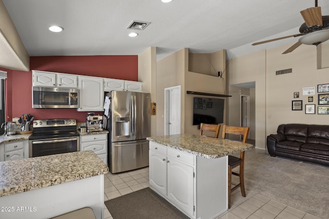 843 E Vera Ln, Tempe, AZ 85284 - kitchen featuring appliances with stainless steel finishes, high vaulted ceiling, ceiling fan, white cabinets, and a breakfast bar