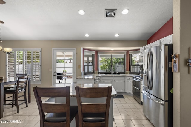 843 E Vera Ln, Tempe, AZ 85284 - kitchen with stainless steel appliances, a sink, light tile patterned floors, white cabinetry, and healthy amount of natural light