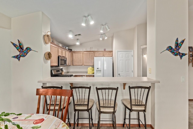 kitchen featuring vaulted ceiling, visible vents, a peninsula, and stainless steel appliances