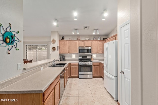 kitchen featuring light tile patterned floors, stainless steel appliances, a sink, visible vents, and a peninsula