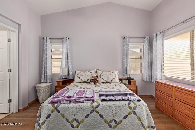 bedroom with baseboards, vaulted ceiling, and wood finished floors