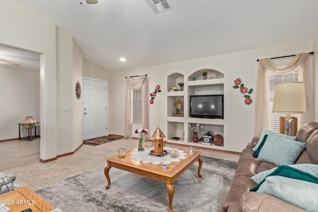 living area with lofted ceiling, light tile patterned floors, baseboards, visible vents, and built in features