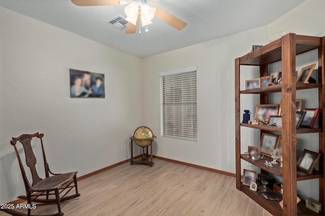 living area with baseboards, visible vents, light wood-style flooring, and a ceiling fan