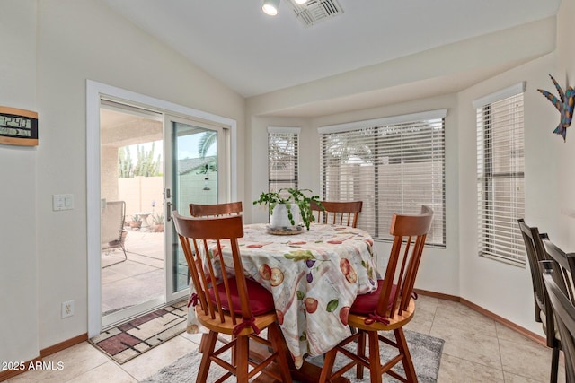 dining area featuring light tile patterned flooring, baseboards, vaulted ceiling, and visible vents