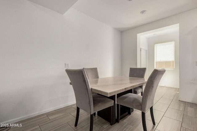dining area featuring baseboards and wood tiled floor