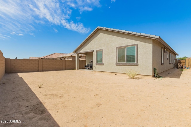 back of property with a fenced backyard and stucco siding