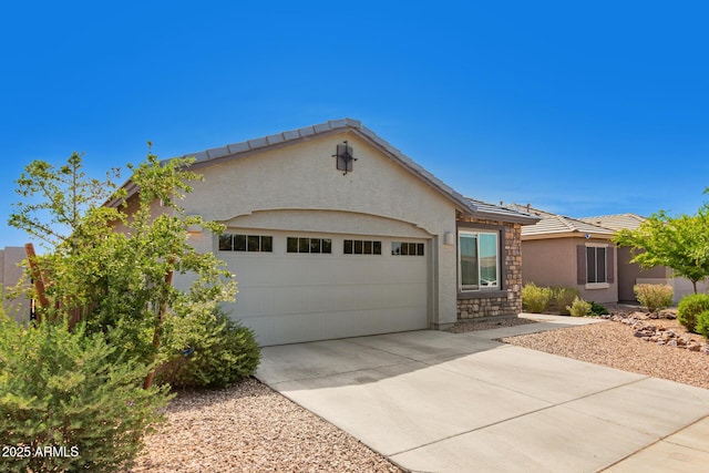 ranch-style home with a tiled roof, a garage, concrete driveway, stone siding, and stucco siding