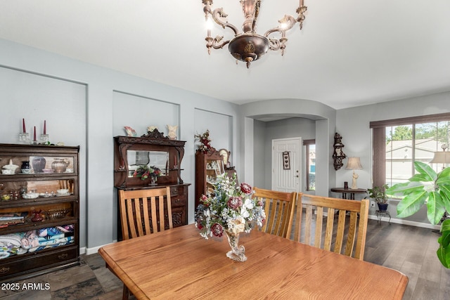 dining space featuring arched walkways, an inviting chandelier, dark wood-style floors, and baseboards