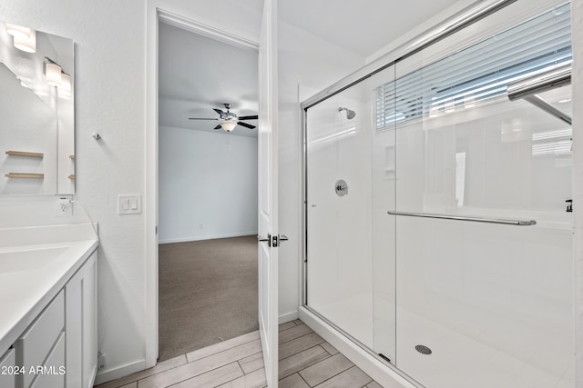 full bathroom with ceiling fan, vanity, wood finished floors, and a stall shower