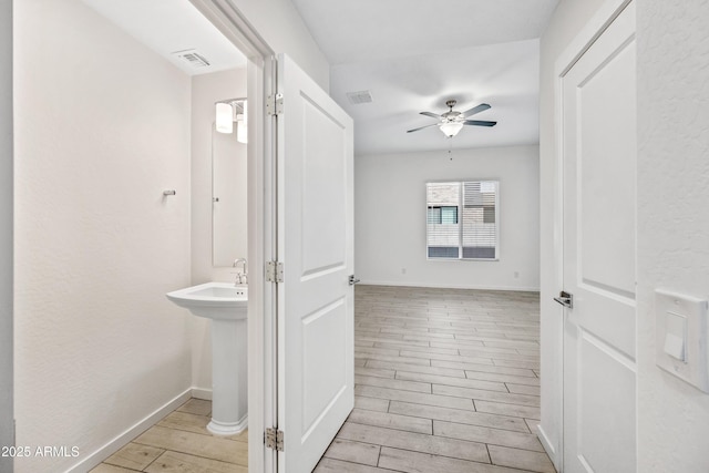 hall featuring visible vents, light wood finished floors, and baseboards