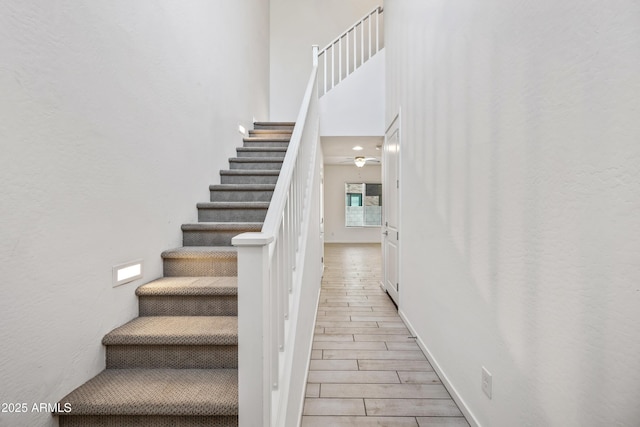 stairs with wood finished floors and a high ceiling