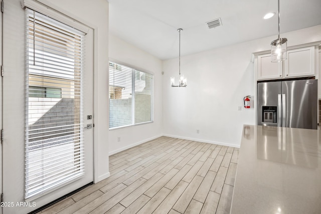 kitchen featuring white cabinets, light wood-style flooring, baseboards, visible vents, and stainless steel fridge with ice dispenser