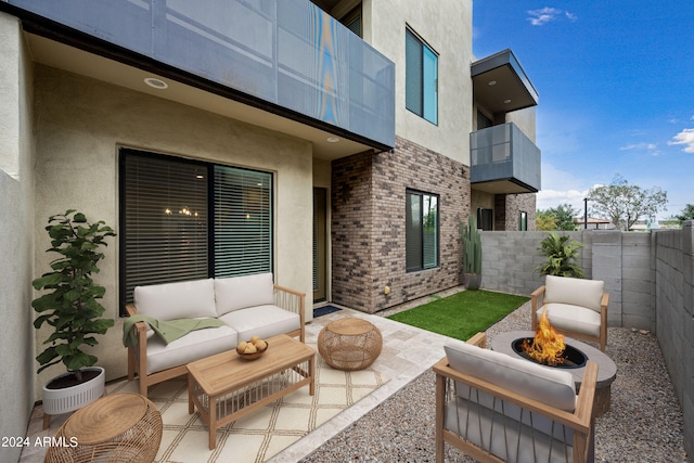 view of patio / terrace with a fenced backyard, an outdoor living space with a fire pit, and a balcony