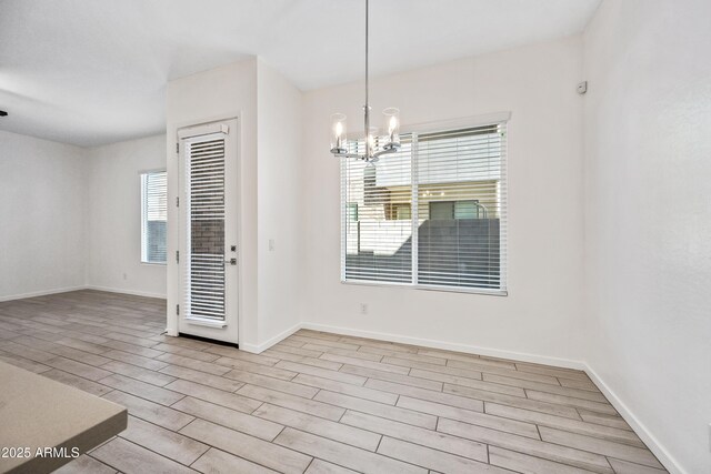 empty room with baseboards, wood finished floors, and a notable chandelier
