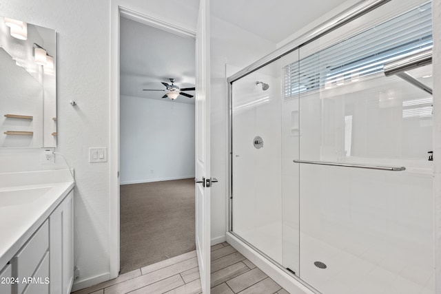 bathroom featuring vanity, ceiling fan, and a shower with door