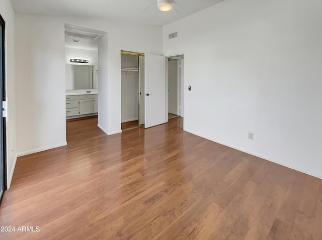 unfurnished bedroom with ensuite bathroom, ceiling fan, a closet, and hardwood / wood-style flooring