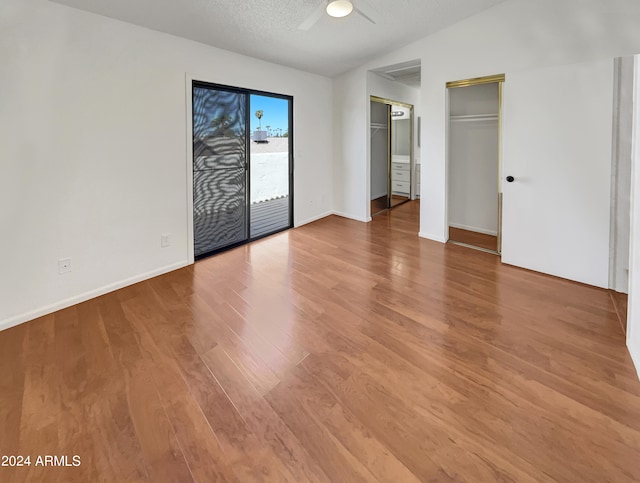 spare room with wood-type flooring, a textured ceiling, lofted ceiling, and ceiling fan